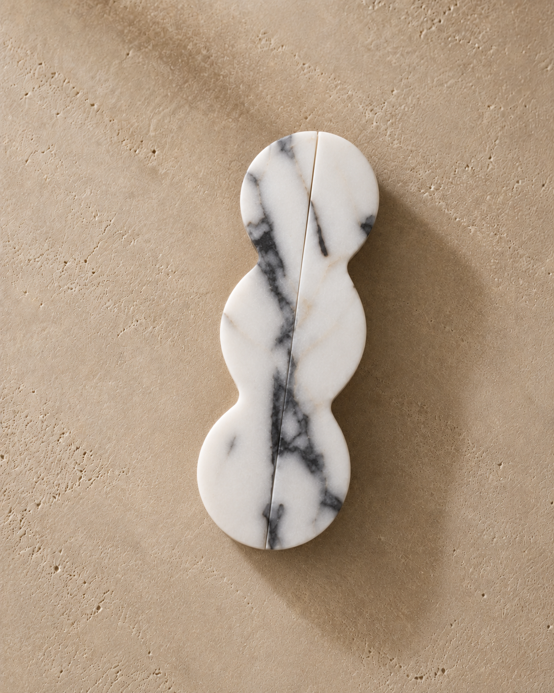 A three-bubble-shaped white marble wall hook with dark gray veining, displayed on a textured beige background.