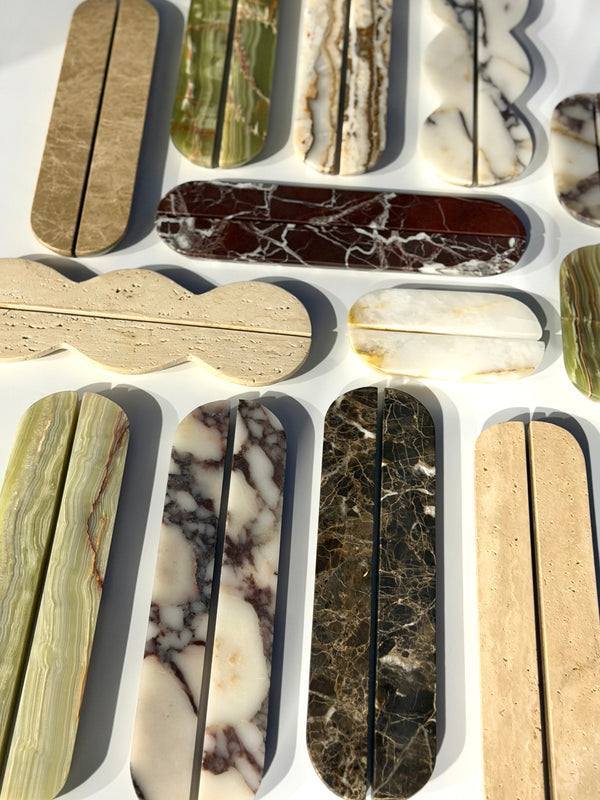 A collection of polished stone elongated bar clasp connectors in various natural marble and granite patterns, arranged on a white background.
