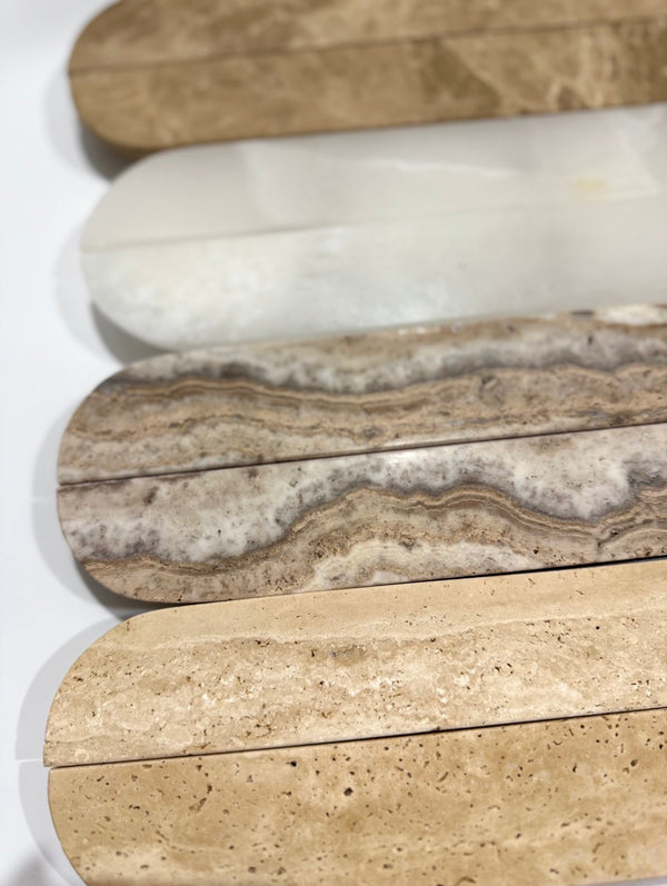 Four polished stone slabs in different natural patterns and colors, arranged vertically on a white background. The stones show variations from light beige and cream to brown, gray, and white marbled textures.