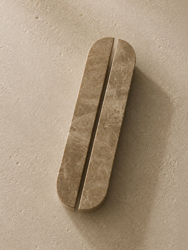 A pair of elongated, rounded bar handles with a warm beige marble texture, shown on a matching textured beige background.