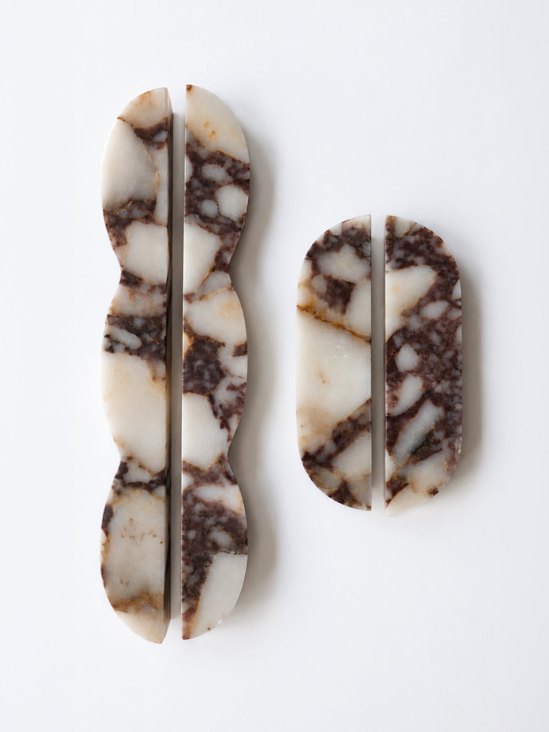 Two carved stone pieces with a natural marbled pattern in cream, brown, and gray, displayed on a clean white background.