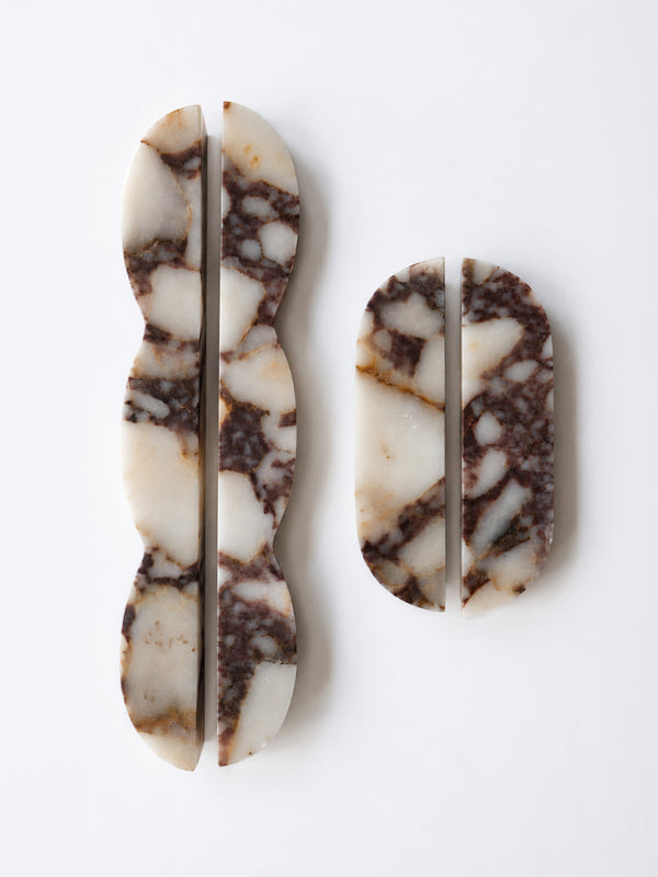 Two carved stone pieces with a natural marbled pattern in cream, brown, and gray, displayed on a clean white background.
