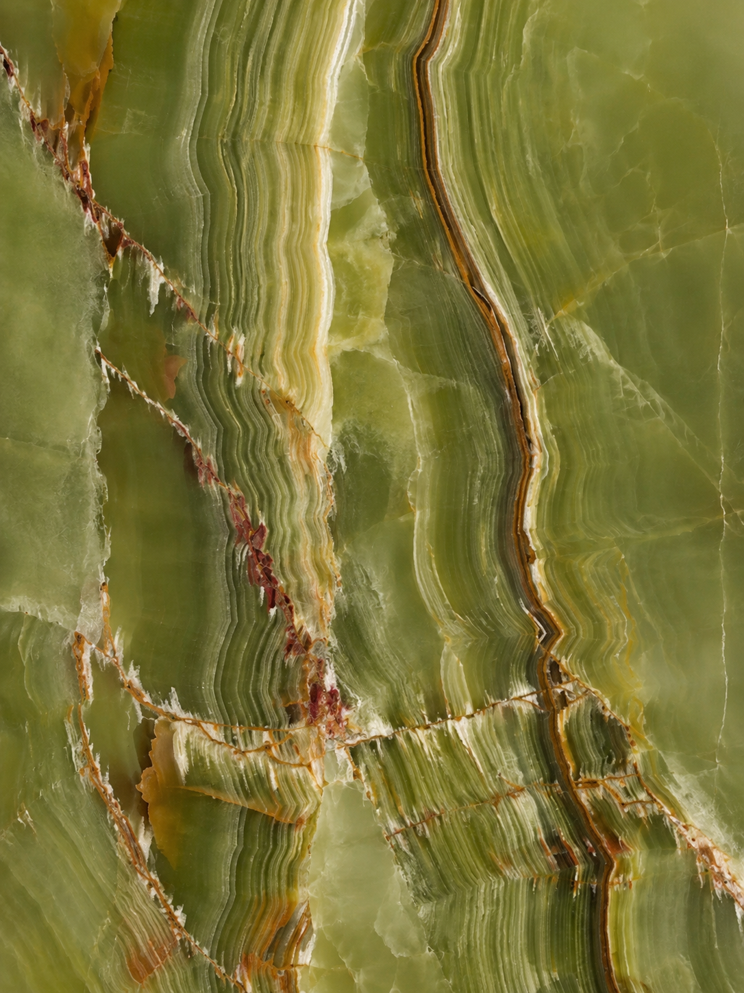 A close-up of a polished stone slab with layered green, beige, and brown veining and natural crystalline texture.