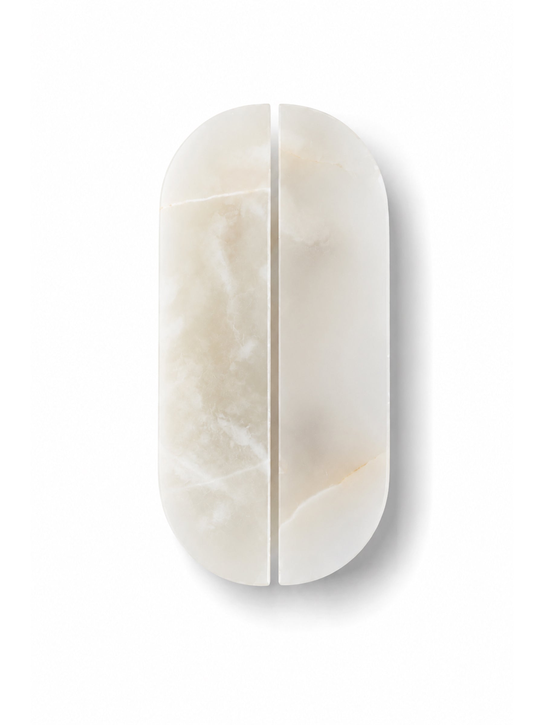 A minimalist, oval-shaped split-screen makeup sponge or applicator made of polished cream-colored marble, shown on a clean white background.