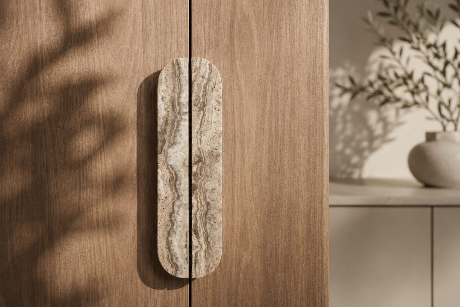 Elongated natural stone bar handle with beige and grey veining mounted on a warm timber cabinet door.